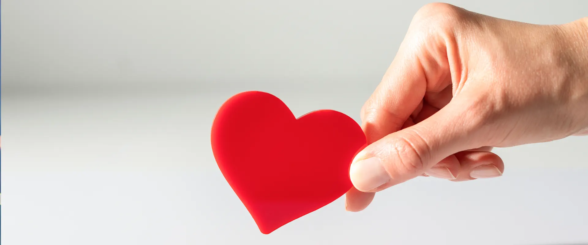 Dedos sujetando corazón de papel